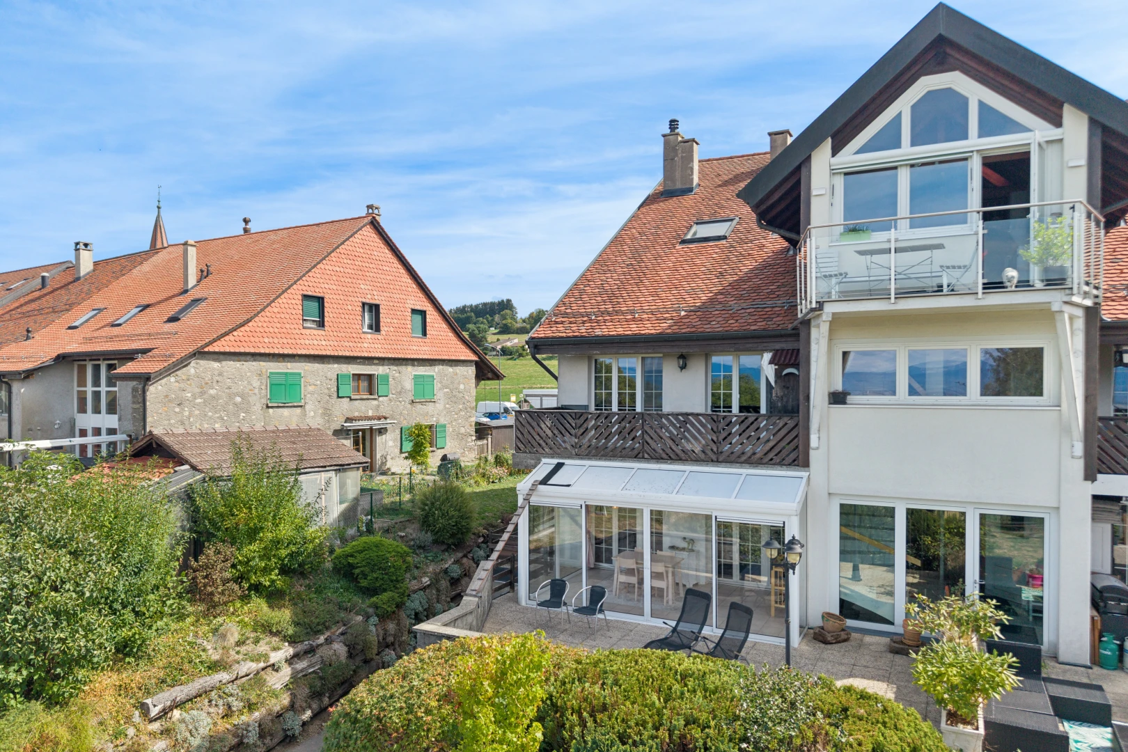 façade avec véranda, cheminée, bardage en stuc, drone view, et day time