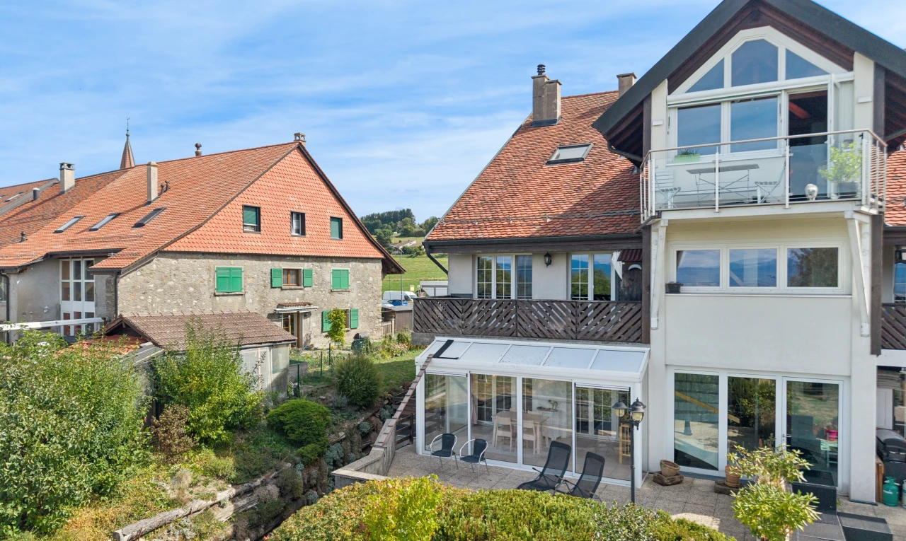 façade avec véranda, cheminée, bardage en stuc, drone view, et day time
