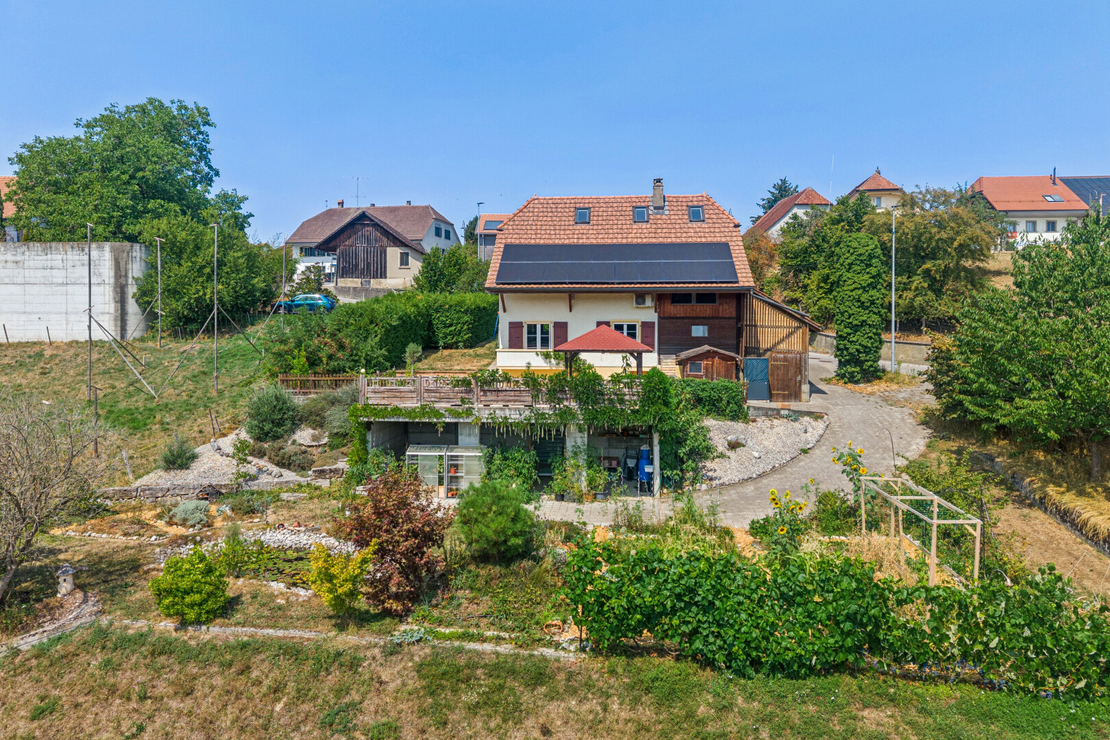 façade avec property visible, panneaux solaires, cheminée, drone view, et day time