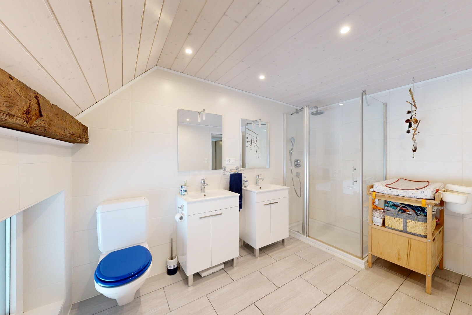 salle de bains avec salle de bain complète, douche, deux lavabos simples, miroir, et toilette