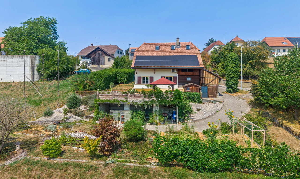 façade avec property visible, panneaux solaires, cheminée, drone view, et day time
