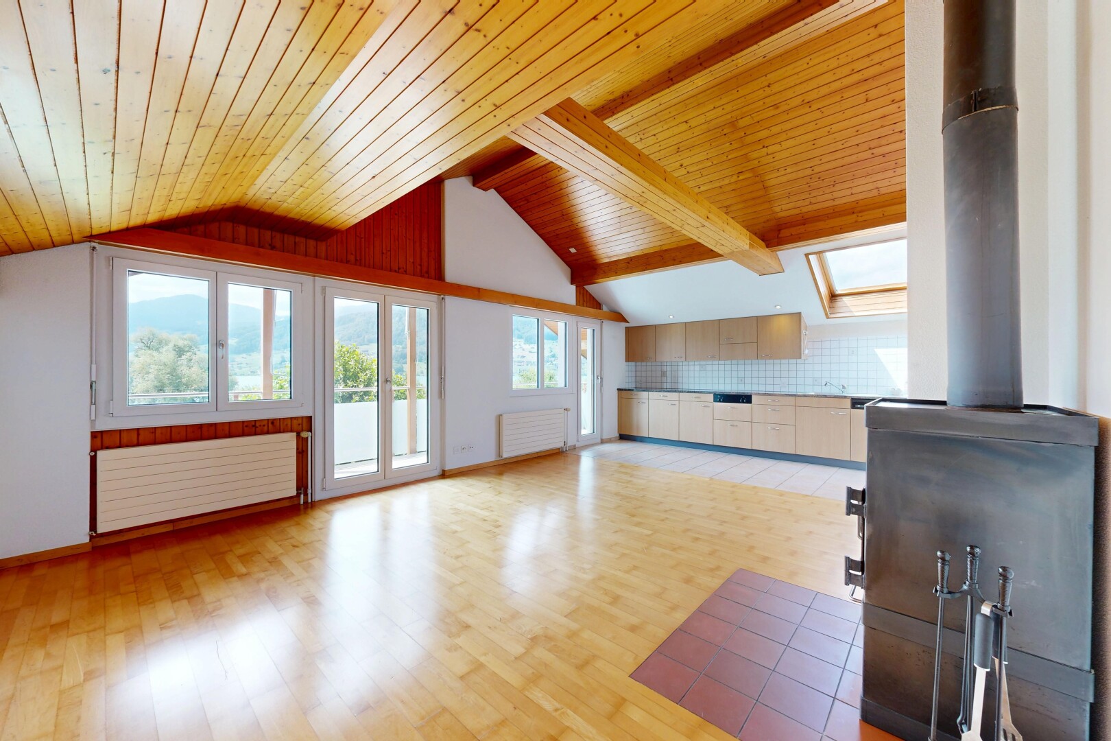 leerer raum mit holzofen, natürliches licht, vaulted ceiling, dachschräge, und wood finish floor