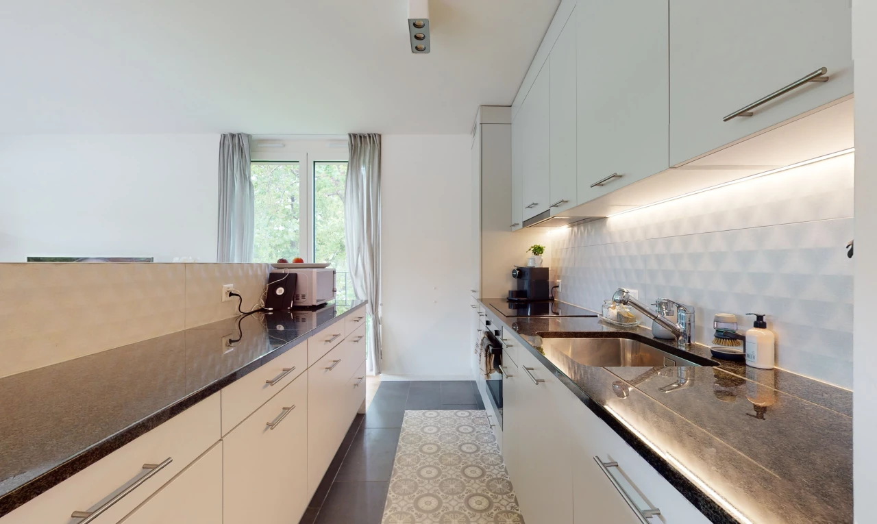 cuisine avec lumière naturelle, cuisinière électrique, meubles blancs, et plan de travail foncé