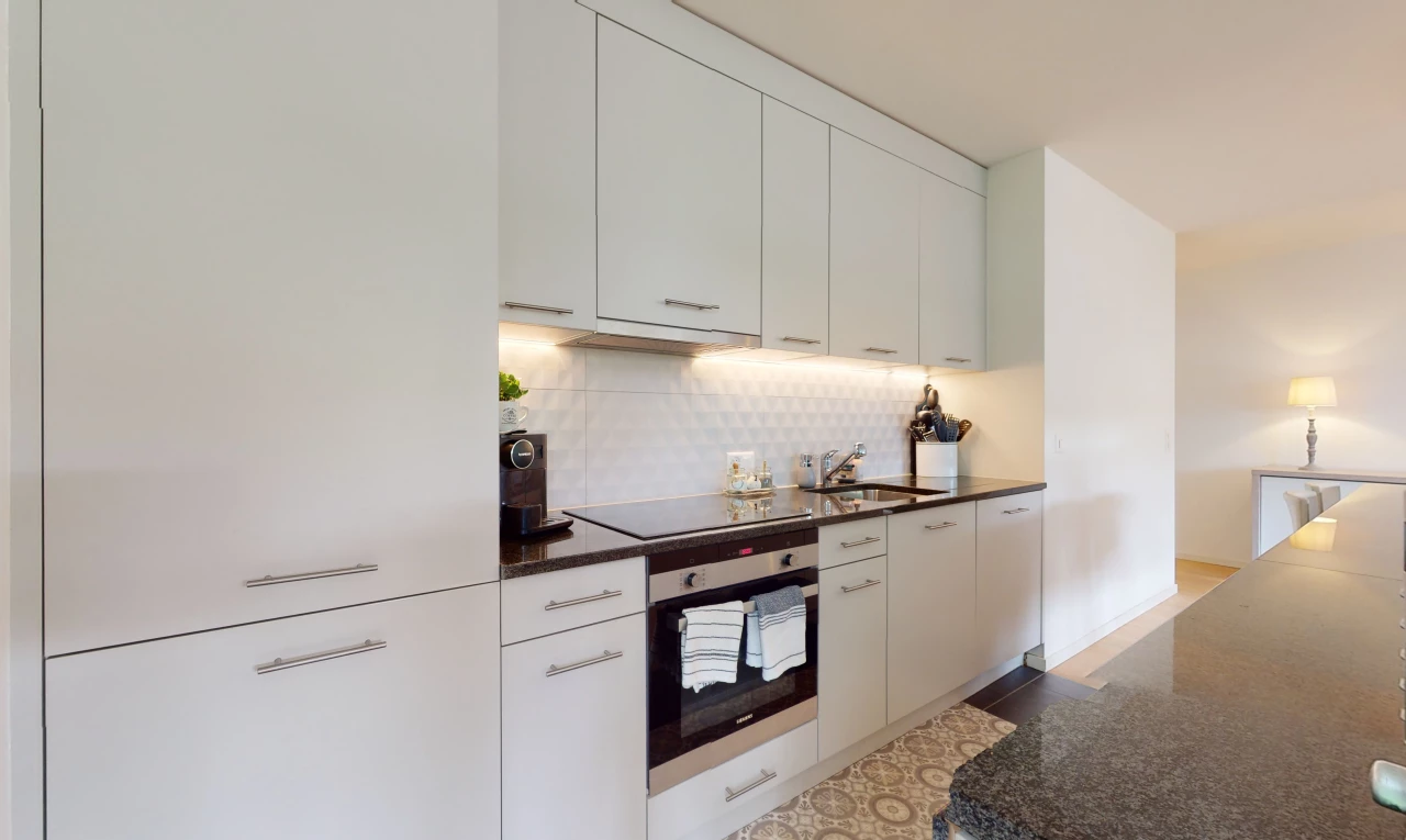 cuisine avec four, cuisinière électrique, meubles blancs, et plan de travail foncé