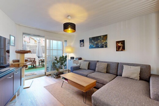 wohnzimmer mit natürliches licht, fernseher, holzfußboden, und gipskartonwand