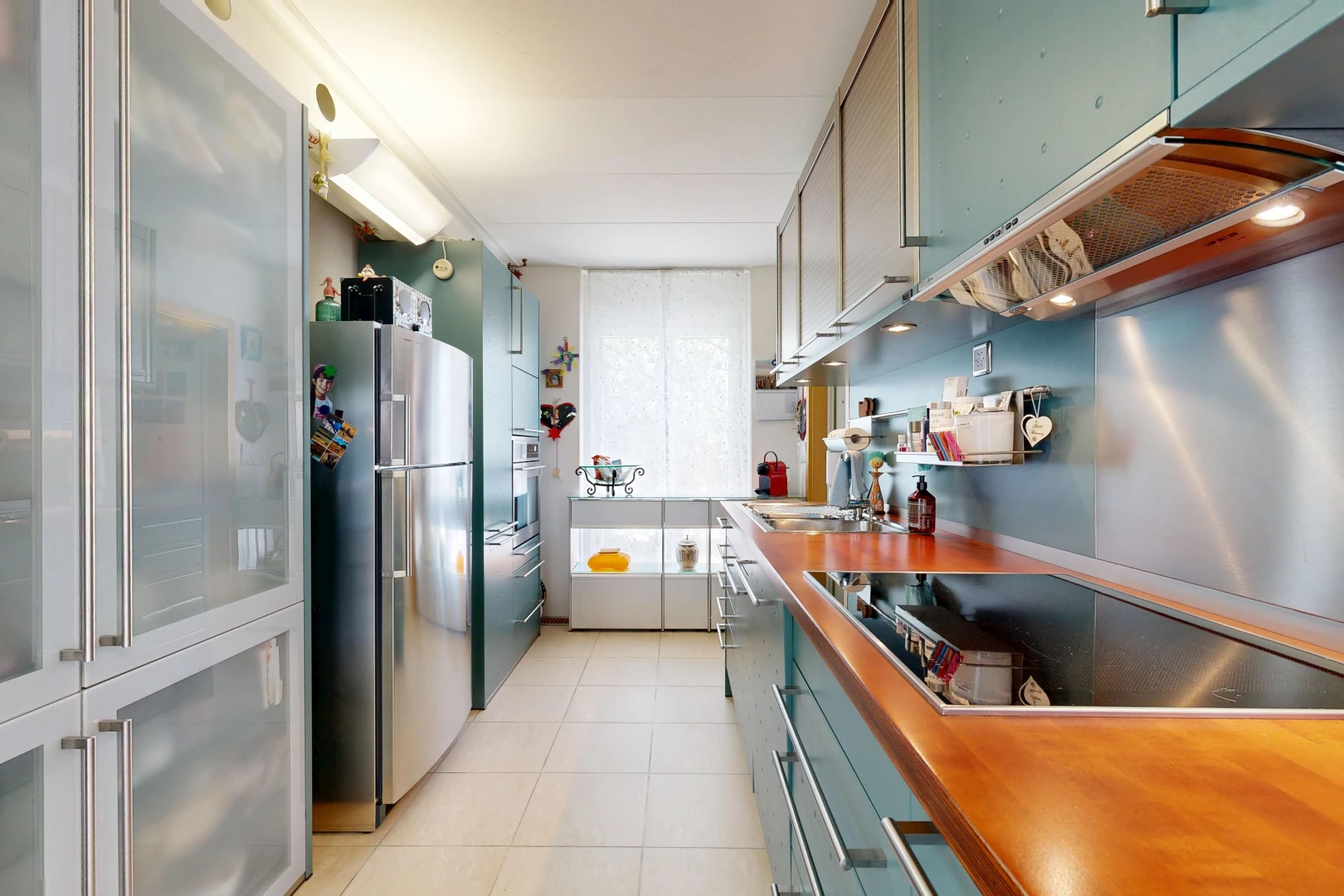 kitchen with freestanding refrigerator, black electric cooktop, and light tile patterned floors