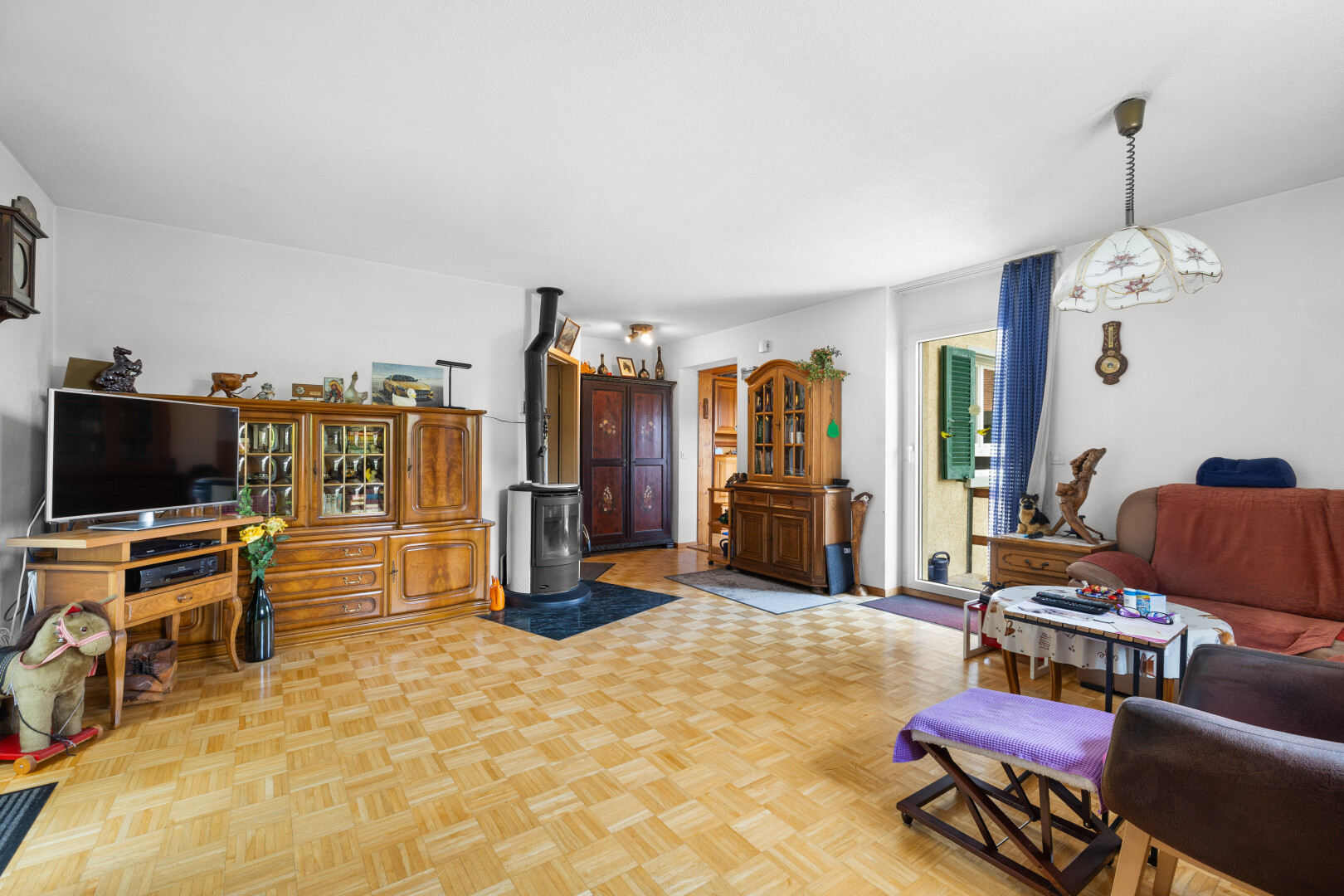 salon avec parquet floor, télévision, poêle à bois, lumière naturelle, et natural light
