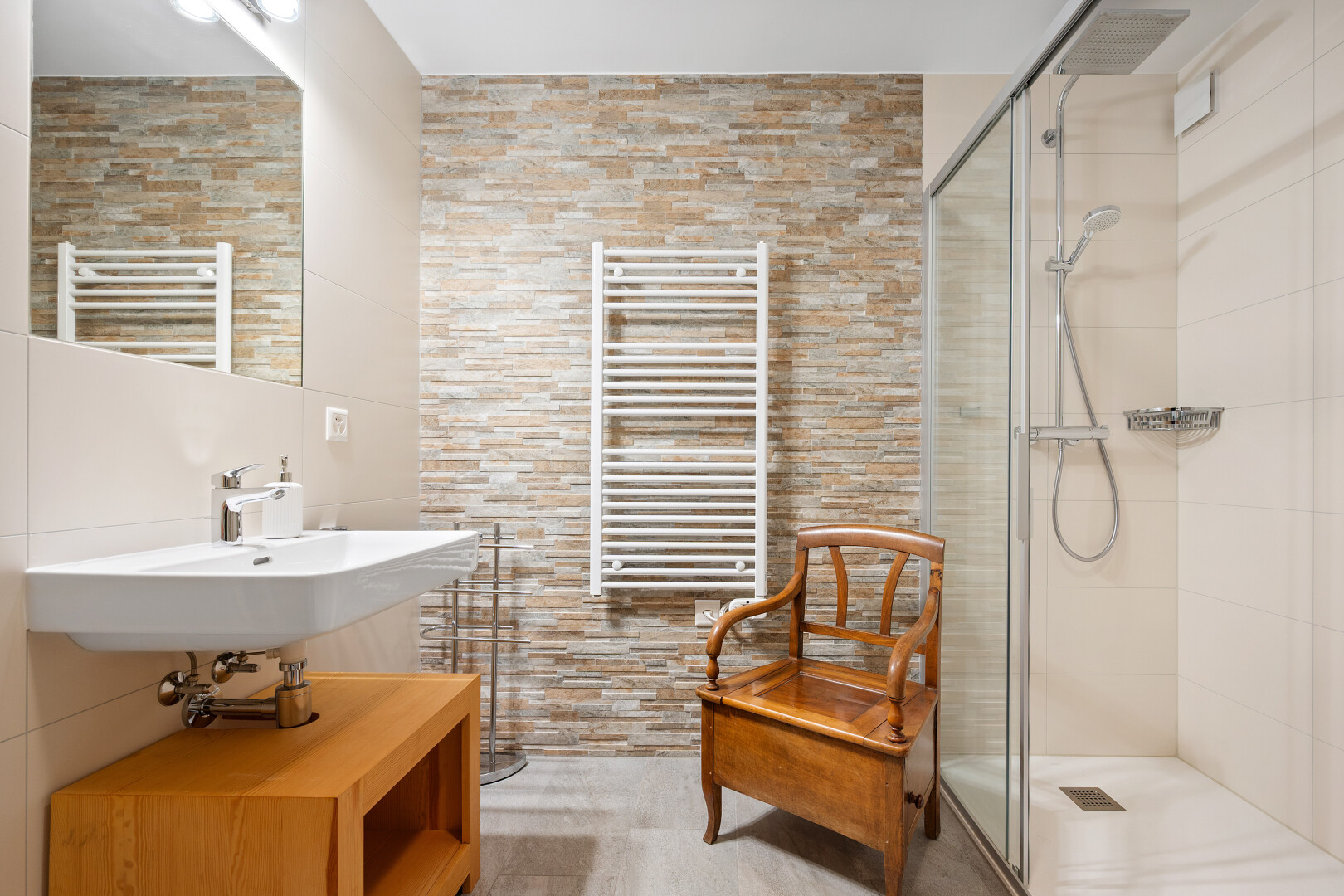 salle de bains avec miroir, mur en pierre, stone wall, radiateur, et inside property