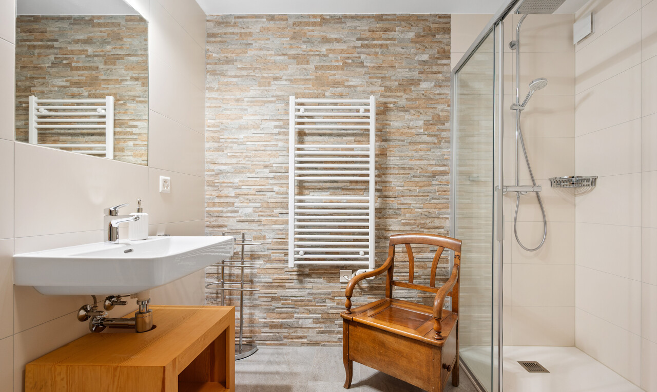 salle de bains avec miroir, mur en pierre, stone wall, radiateur, et inside property
