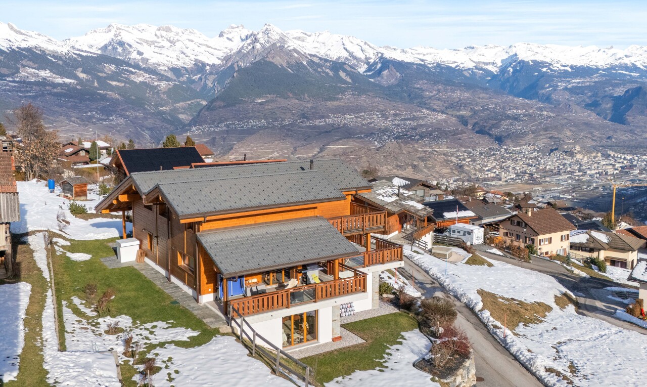 snow covered house with a patio area, a mountain view, and a balcony