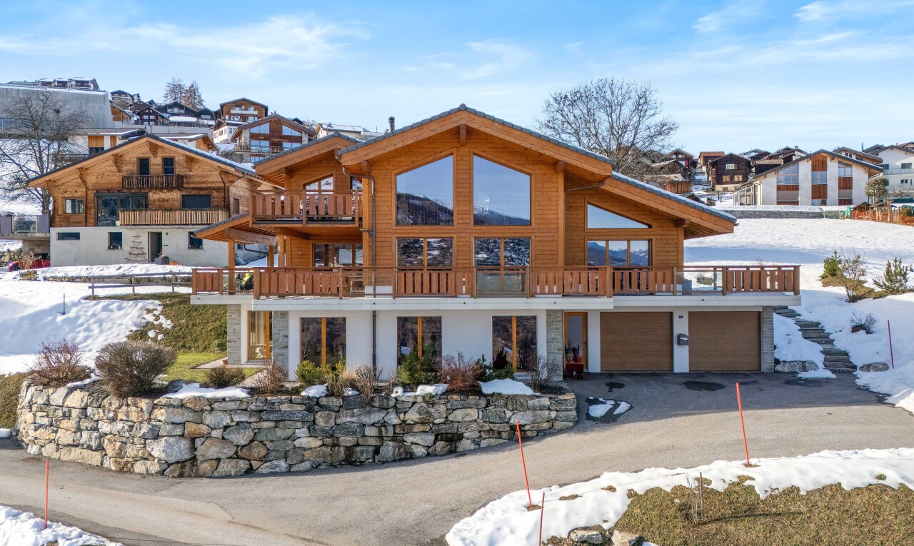 snow covered house with a balcony, an attached garage, and driveway