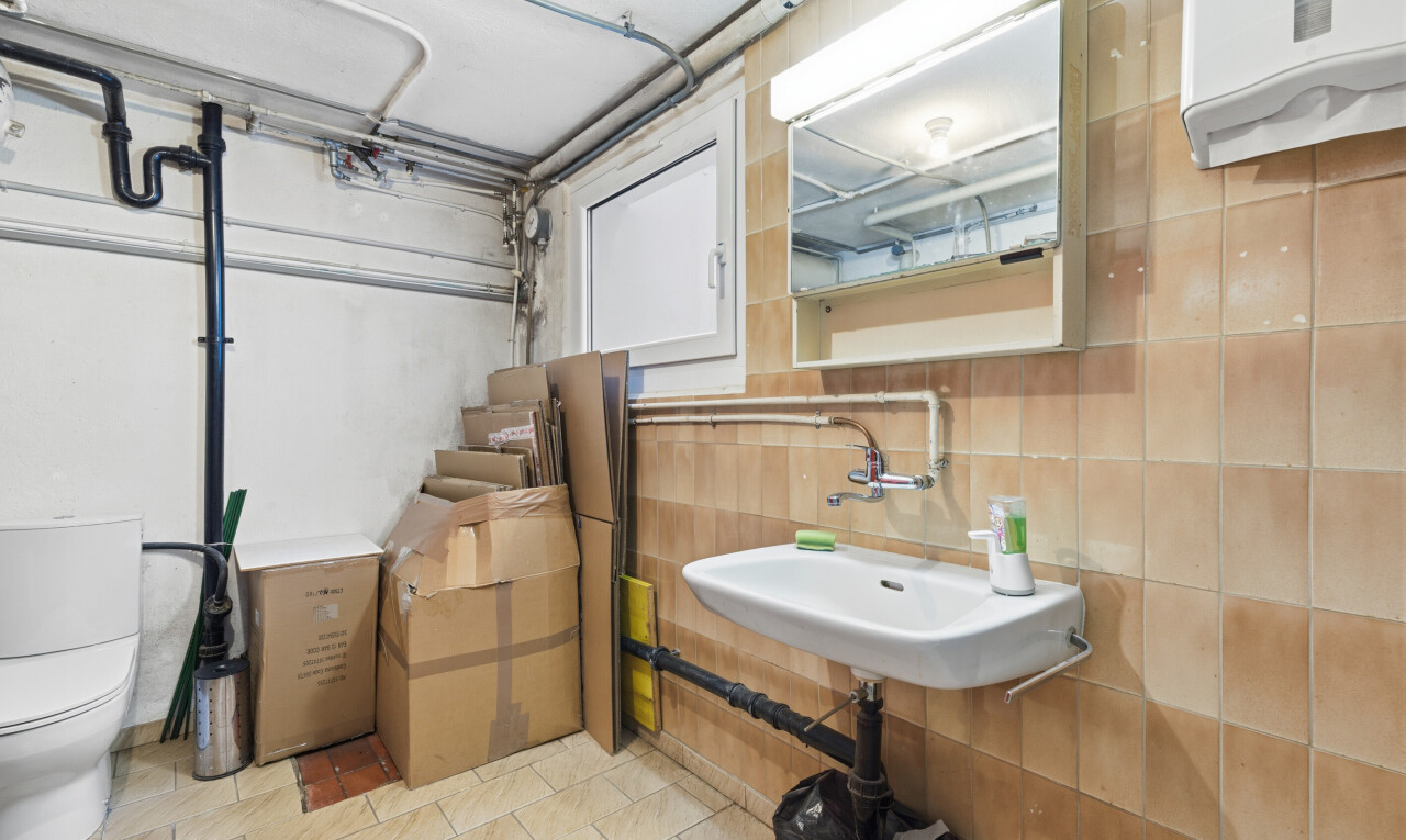 salle de bains avec toilette, miroir, inside property, évier, et light floor