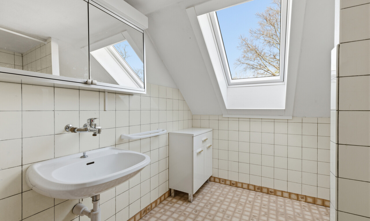 salle de bains avec puits de lumière, tile wall, mur en carrelage, miroir, et vaulted ceiling