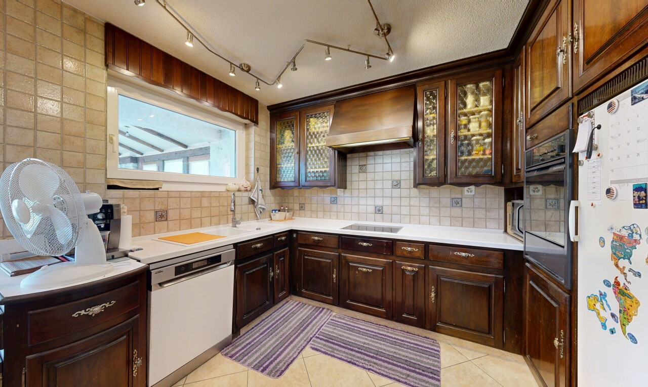cuisine avec armoires élevées, armoires brun foncé, backsplash, dosseret, et lave-vaisselle