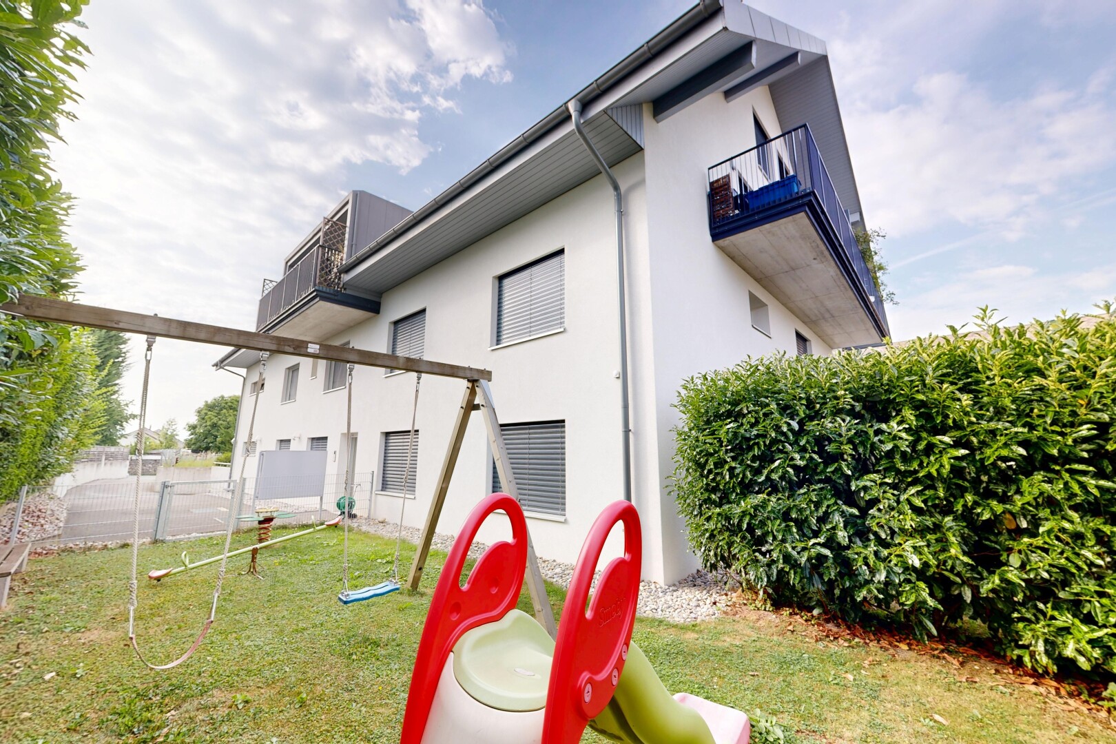 façade avec clôture, property visible, bardage en stuc, pelouse, et balcon