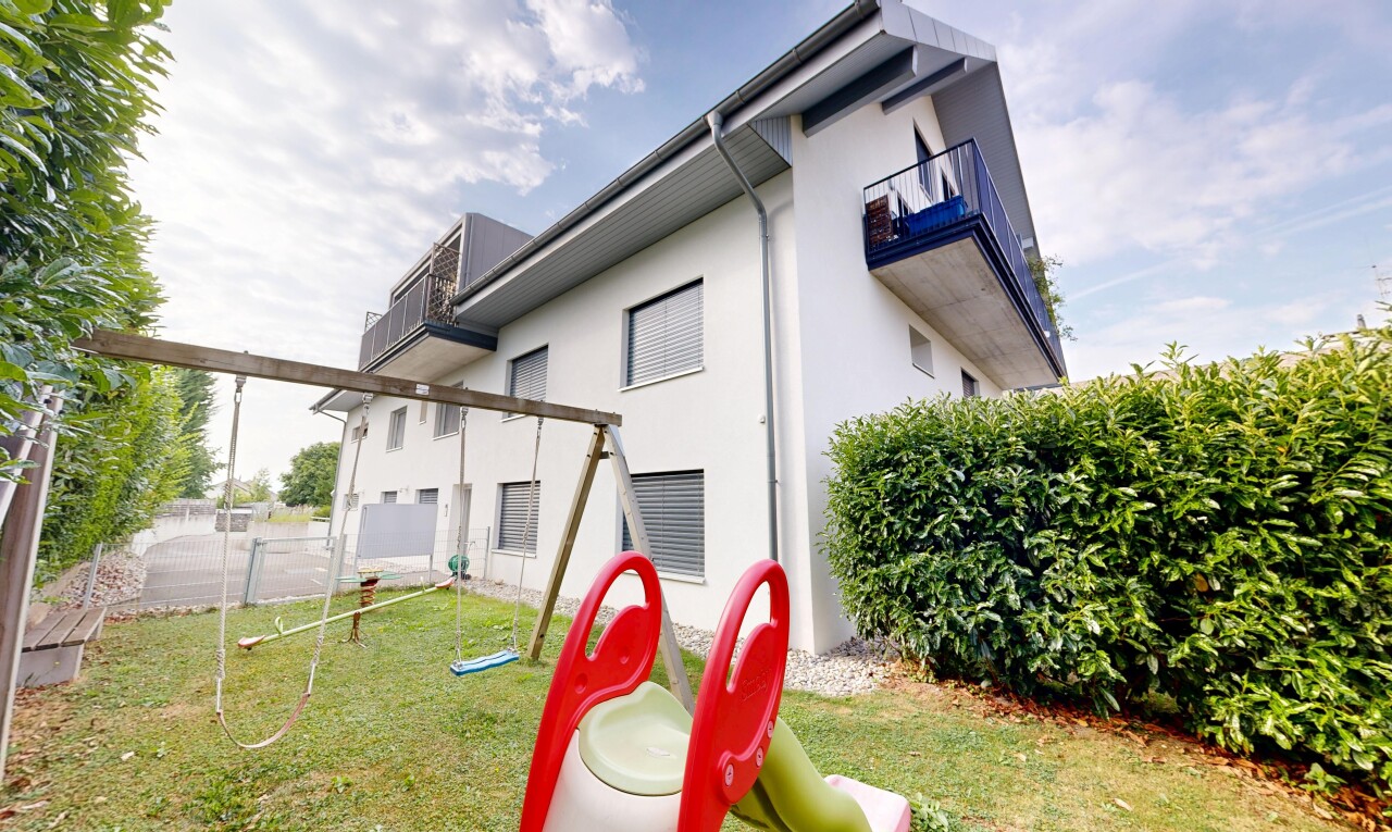 façade avec clôture, property visible, bardage en stuc, pelouse, et balcon