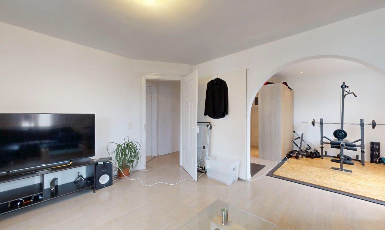 salon avec télévision, cloison sèche, drywall, inside property, et sol en finition bois
