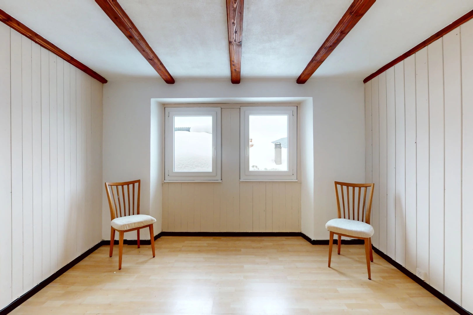 pièce vide avec lumière naturelle, plancher de bois, et poutres apparentes