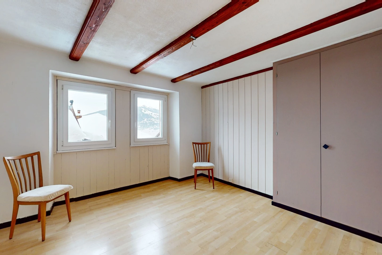 pièce vide avec lumière naturelle, plancher de bois, et poutres apparentes