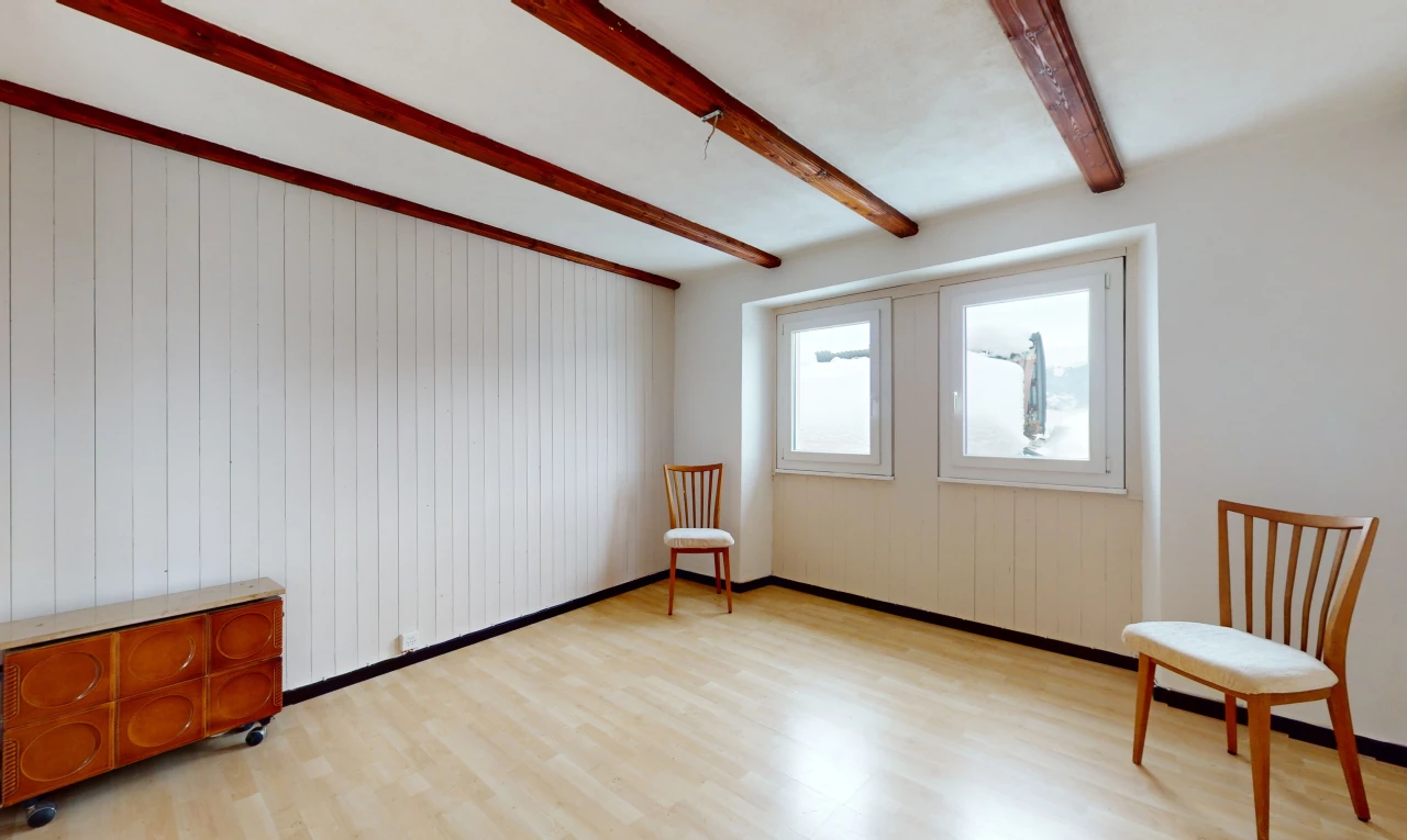 pièce vide avec lumière naturelle, plancher de bois, et poutres apparentes