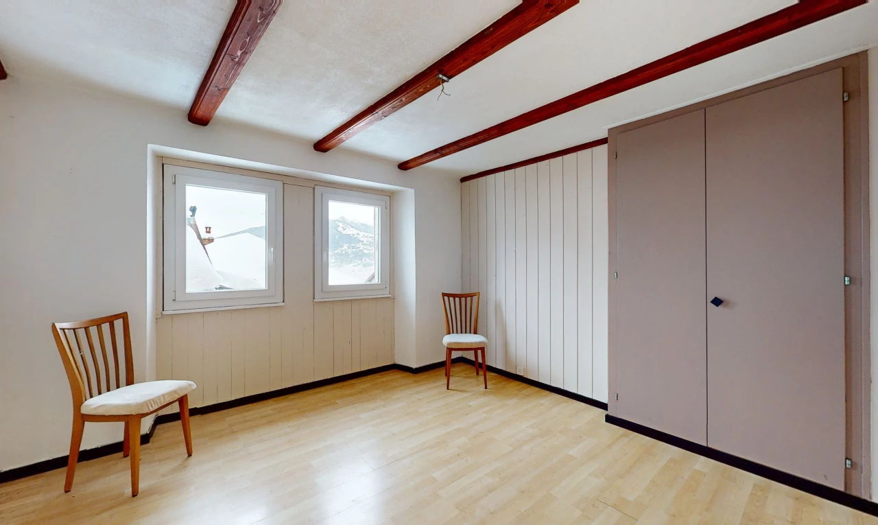 pièce vide avec lumière naturelle, plancher de bois, et poutres apparentes