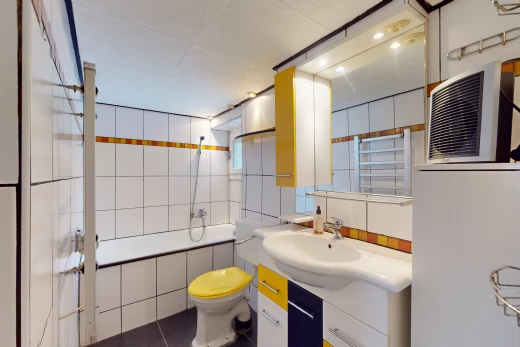 salle de bain avec miroir, meuble-lavabo, vasque, mur carrelé, et toilettes