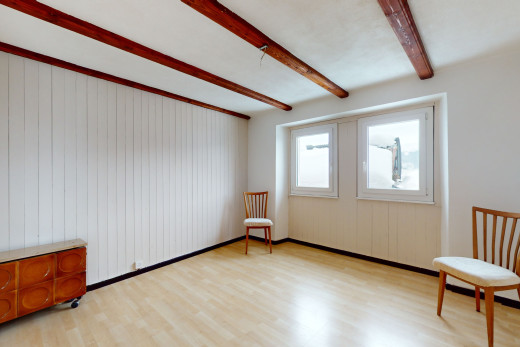 pièce vide avec lumière naturelle, plancher de bois, et poutres apparentes