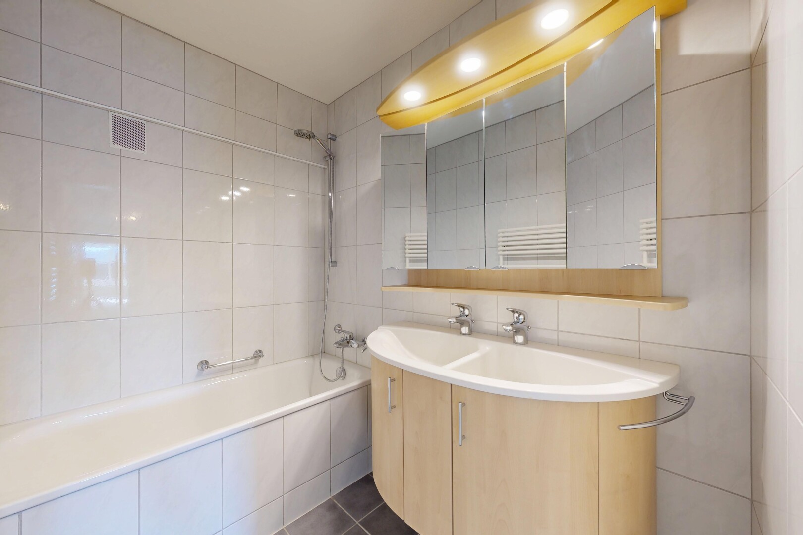 salle de bains avec chauffe-serviettes, tile wall, mur en carrelage, douche-bain combinés, et lavabo (ou coiffeuse selon le contexte)