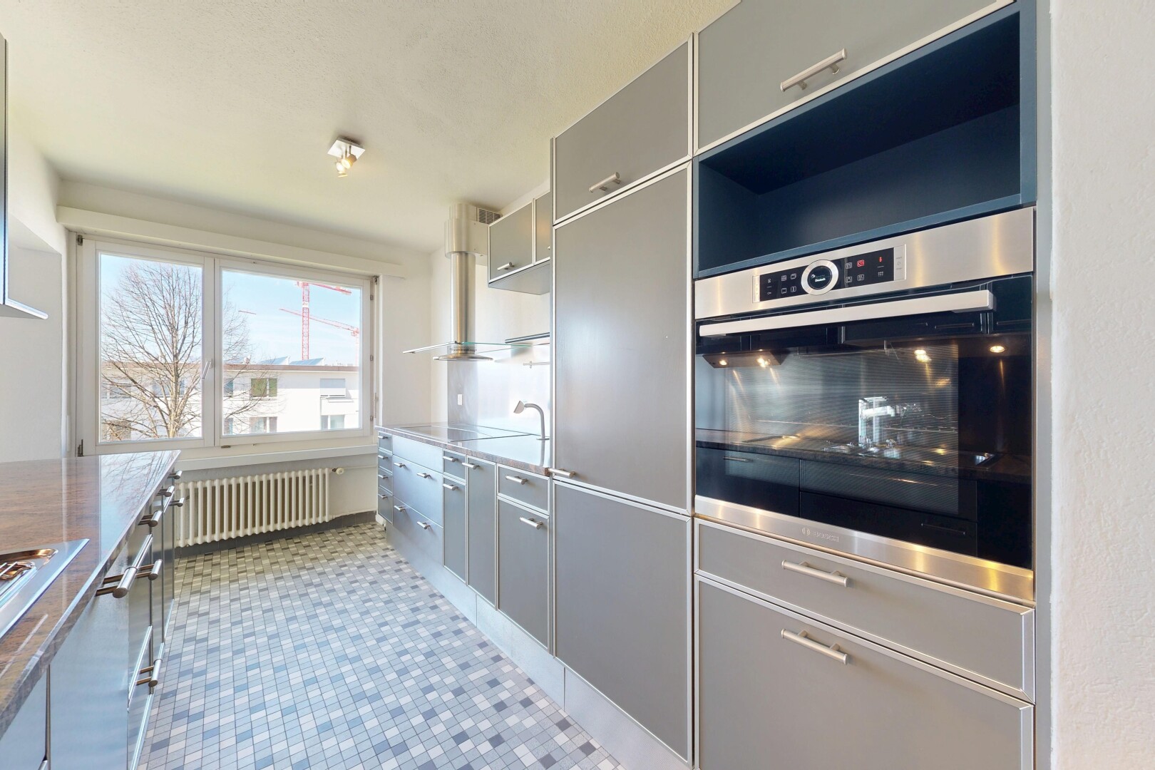 cuisine avec day time, radiateur, inside property, armoires grises, et gray cabinets