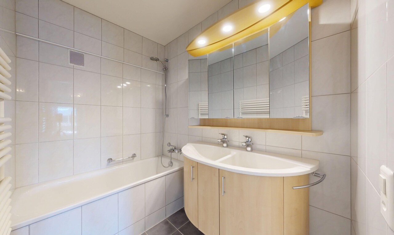 salle de bains avec chauffe-serviettes, tile wall, mur en carrelage, douche-bain combinés, et lavabo (ou coiffeuse selon le contexte)