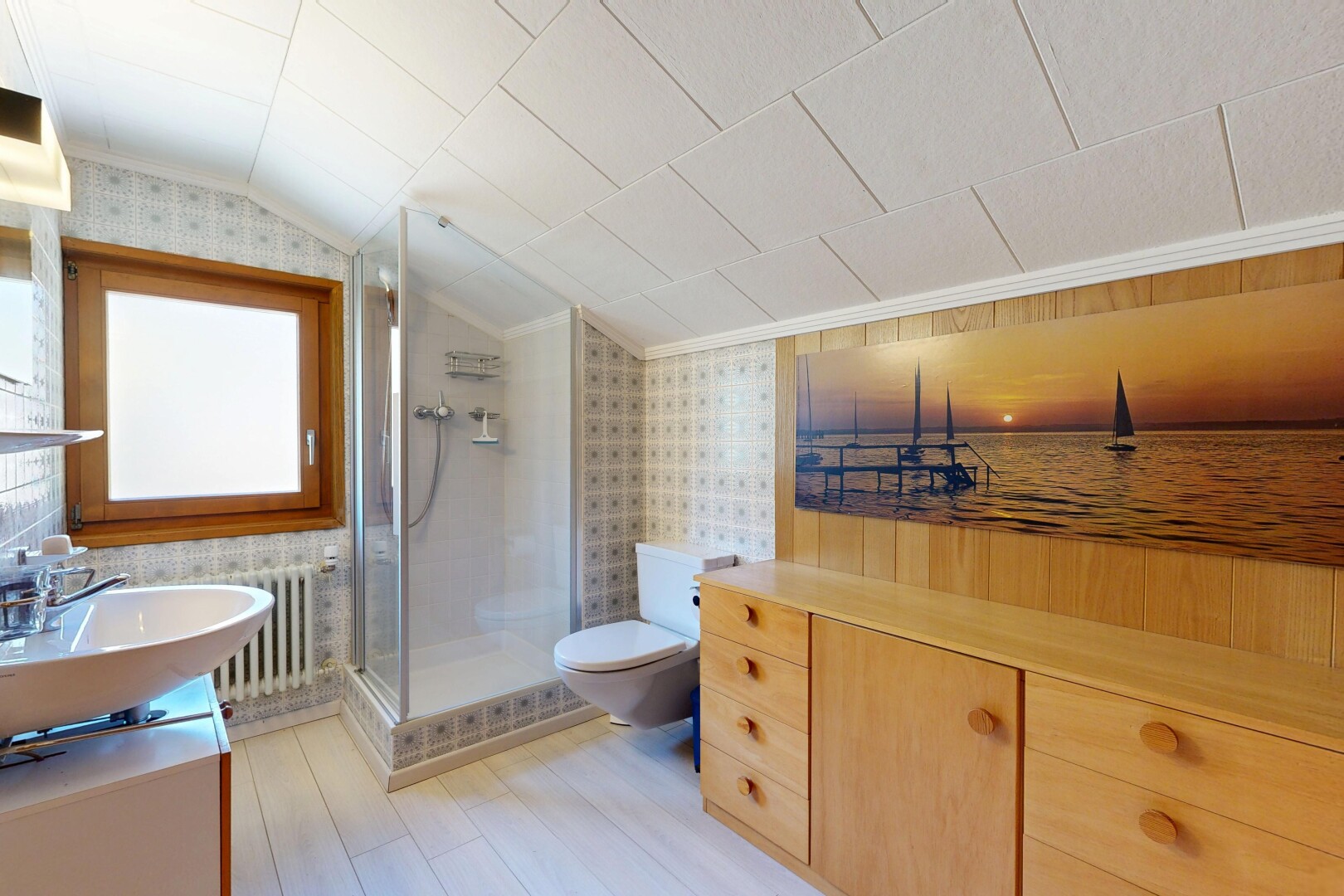 salle de bains avec lavabo (ou coiffeuse selon le contexte), toilette, douche, mur en papier peint, et wallpaper wall