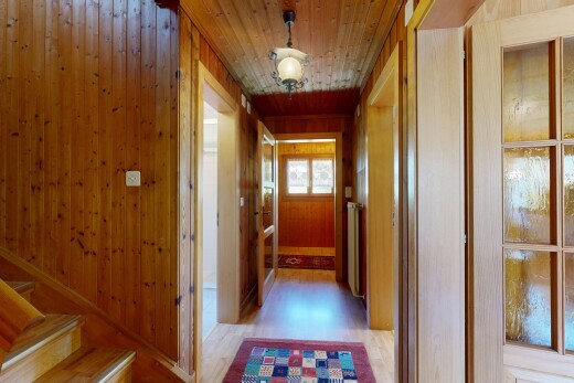 corridor with light wood finished floors, wooden walls, wood ceiling, and radiator