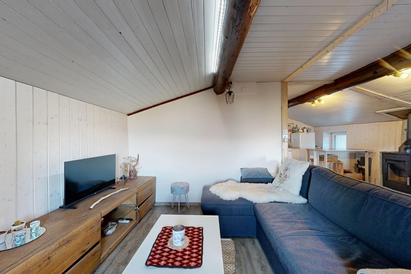 salon avec mur en bois, wood wall, plafond voûté, vaulted ceiling, et télévision