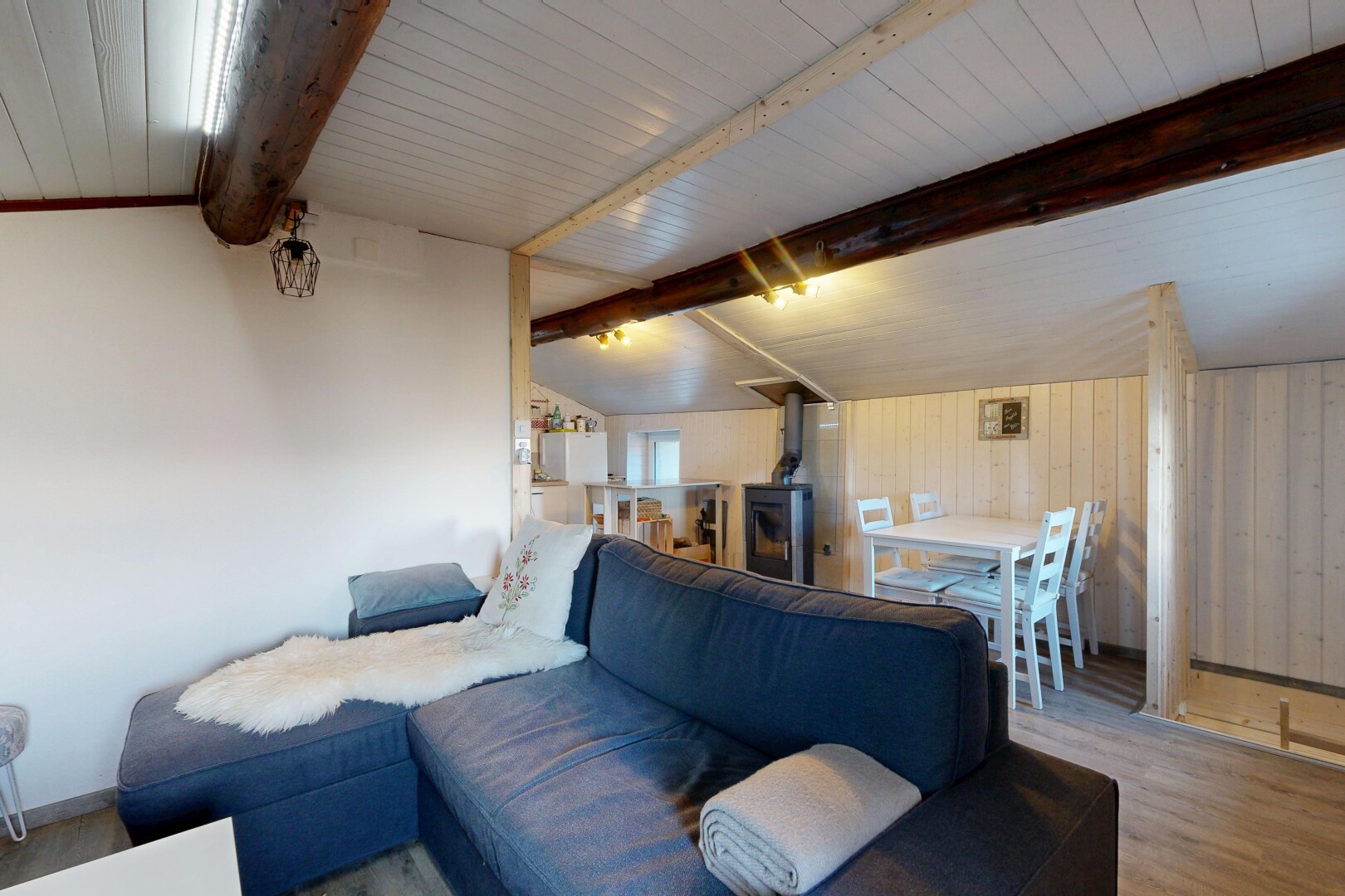 salon / salle à manger avec plafond voûté, vaulted ceiling, poêle à bois, sol en finition bois, et wood finish floor