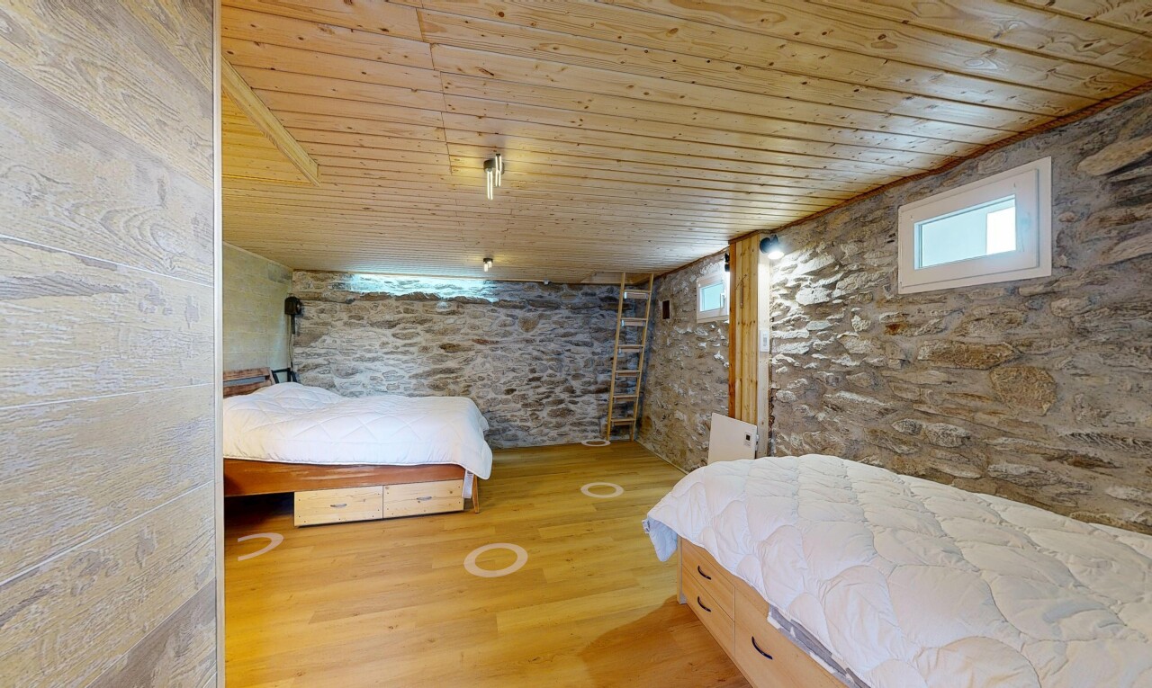 chambre avec mur en pierre, stone wall, plafond en bois, wood ceiling, et sol en finition bois
