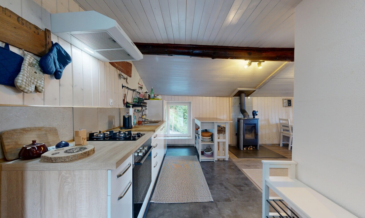 cuisine avec poêle à bois, lumière naturelle, hotte, concrete floor, et sol en béton