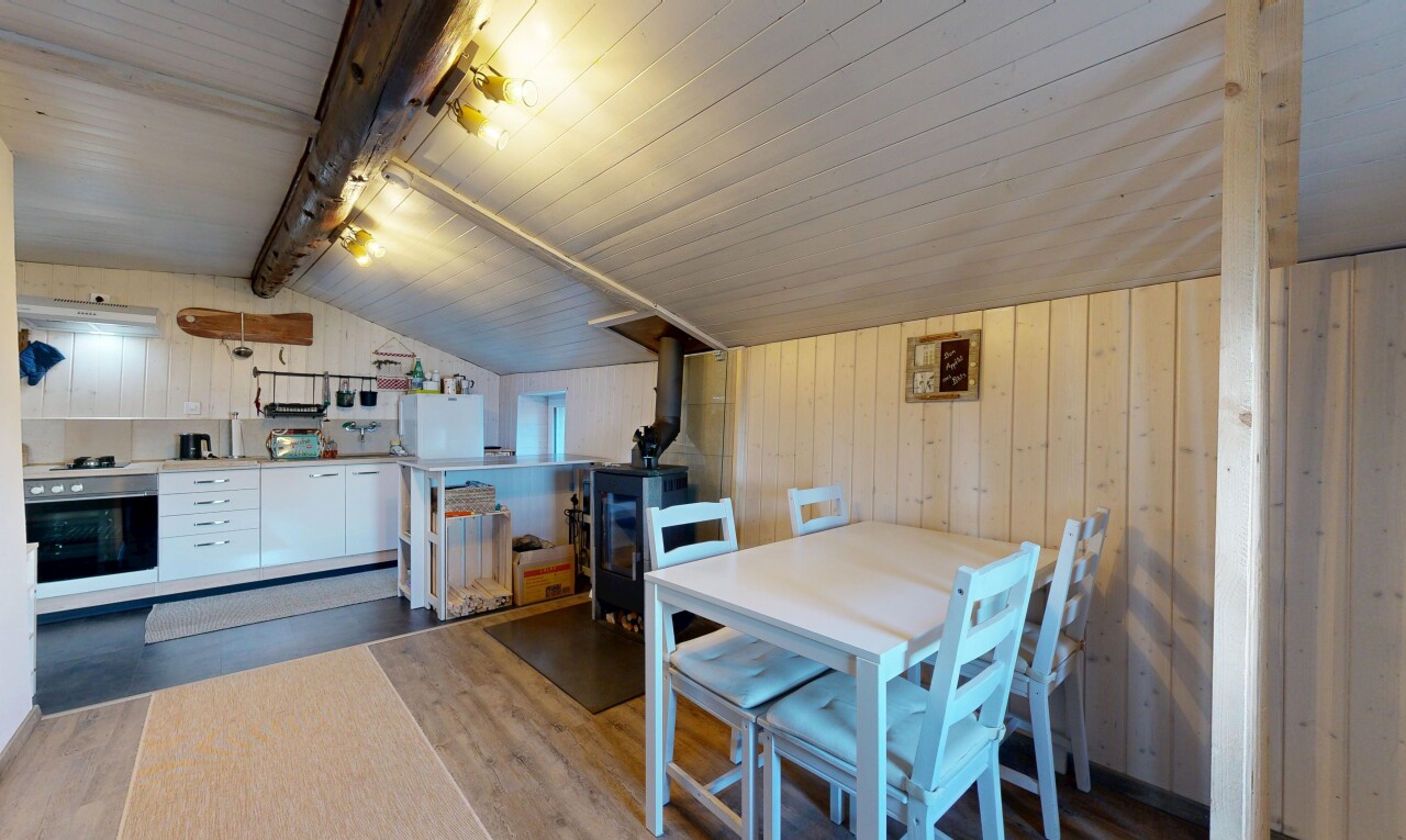 salle à manger avec vaulted ceiling, plafond voûté, wood wall, mur en bois, et poêle à bois