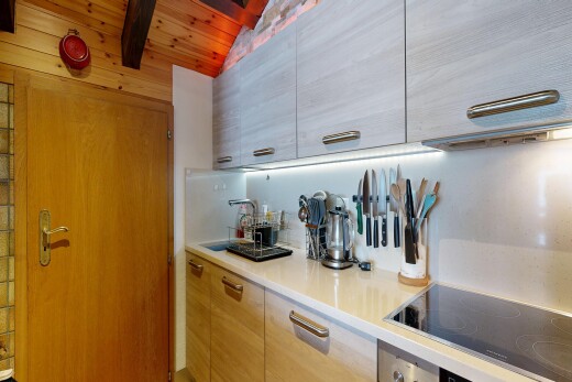 kitchen with black electric stovetop, light countertops, modern cabinets, and vaulted ceiling with beams