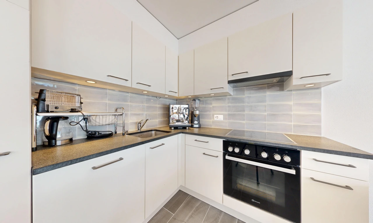 cuisine avec four, plans de travail, dark countertops, light floor, et hotte