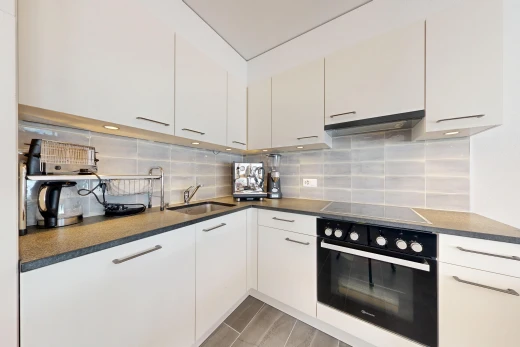 cuisine avec four, plans de travail, dark countertops, light floor, et hotte
