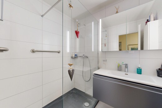 bathroom with vanity, a walk in shower, and tile walls