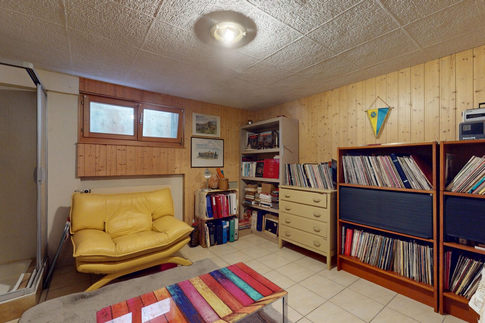 wohnzimmer mit keller, fliesenboden, natürliches licht, und holzwand