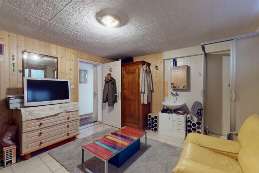 wohnzimmer mit holzwand, fernseher, und fliesenboden