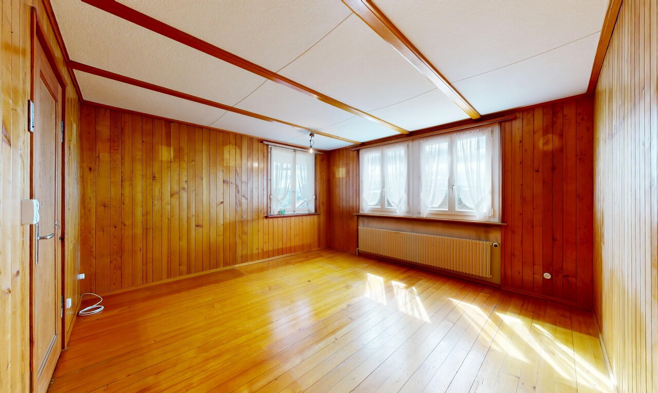 empty room with radiator, light wood-type flooring, and wooden walls