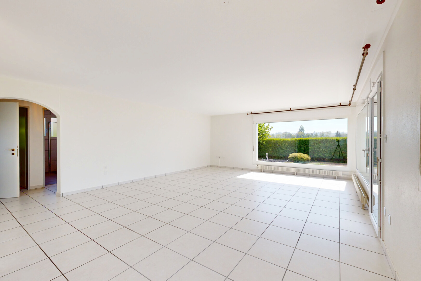 leerer raum mit light floor, gewölbte gehwege, drywall, gipskartonwand, und tile floor