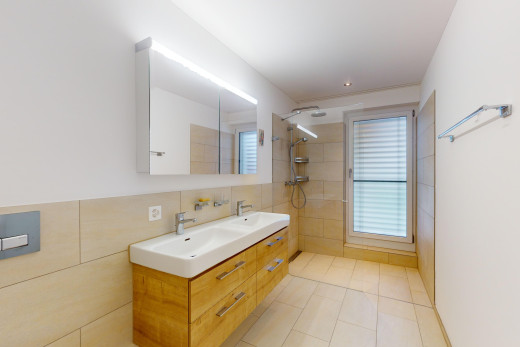 bathroom featuring double vanity, a walk in shower, tile walls, light tile patterned flooring, and healthy amount of natural light