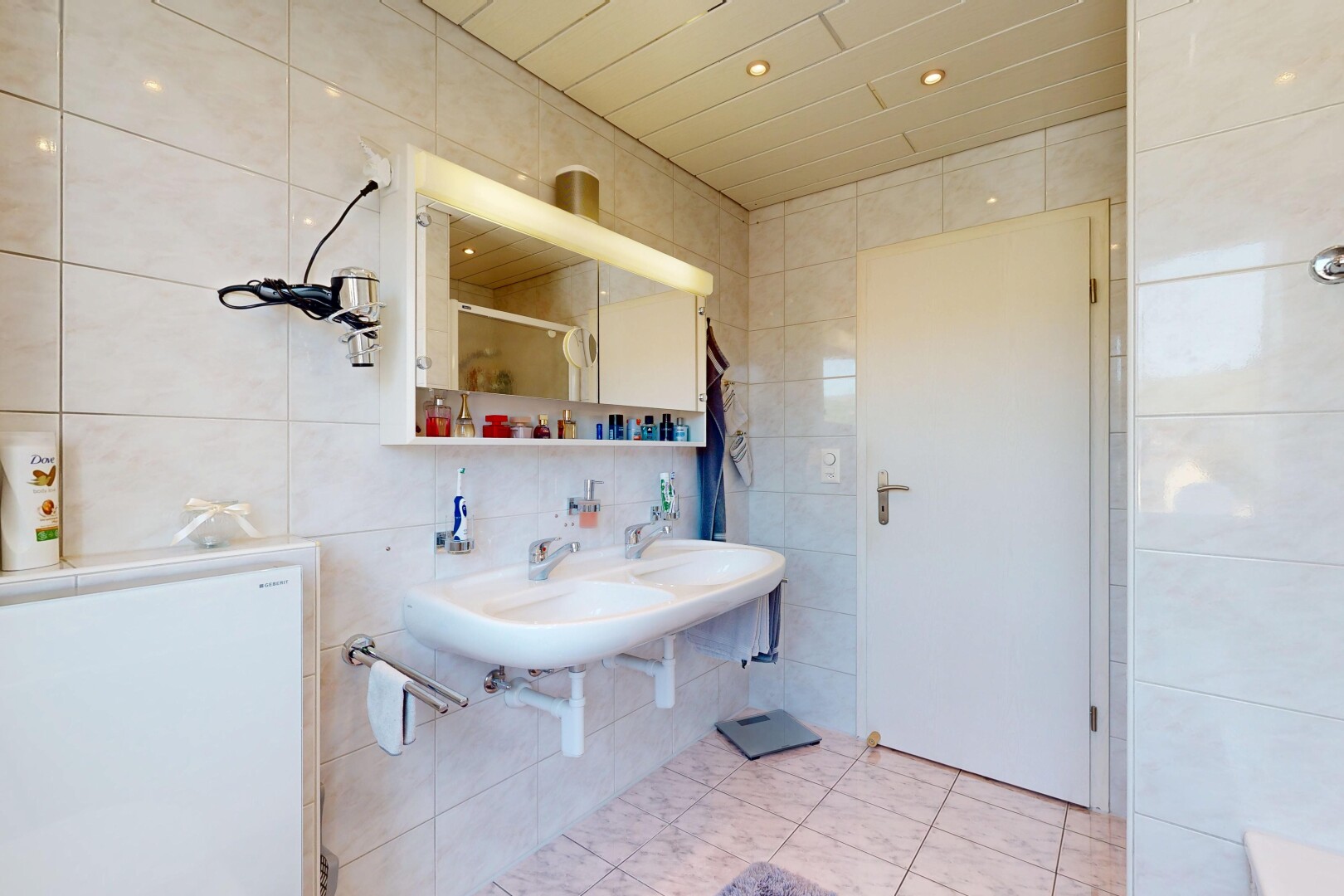 bathroom featuring tile walls, light tile patterned floors, double sink, recessed lighting, and a shower