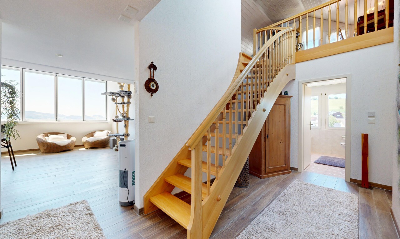 stairway with wood finished floors and a high ceiling