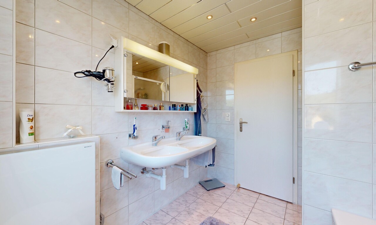 bathroom featuring tile walls, light tile patterned floors, double sink, recessed lighting, and a shower