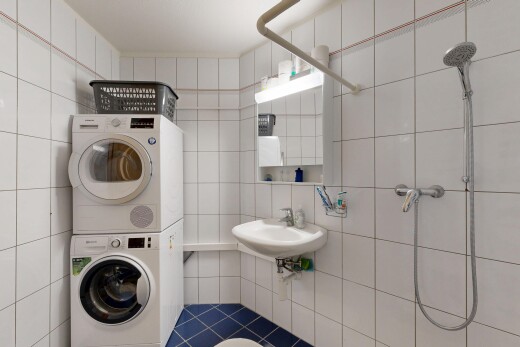 laundry area with tile walls, stacked washer / drying machine, and tile patterned floors